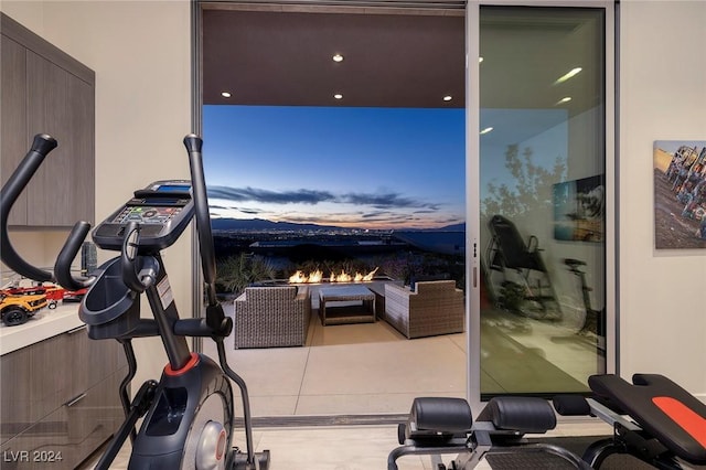 exercise area featuring a fireplace and light tile patterned floors