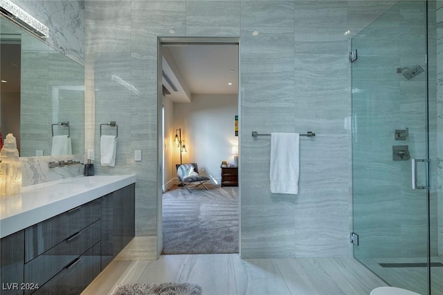 bathroom featuring vanity, a shower with shower door, and tile walls