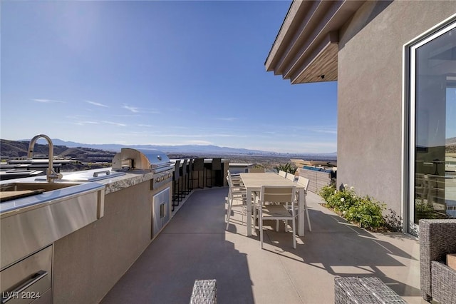 view of patio with a grill, a mountain view, and sink