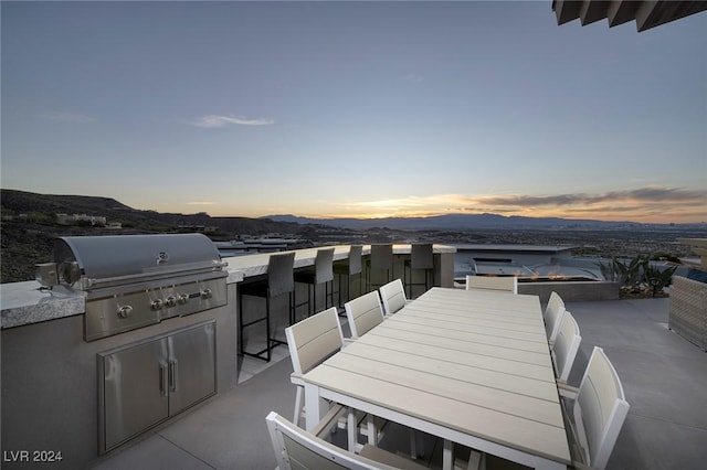 patio terrace at dusk featuring a mountain view and grilling area