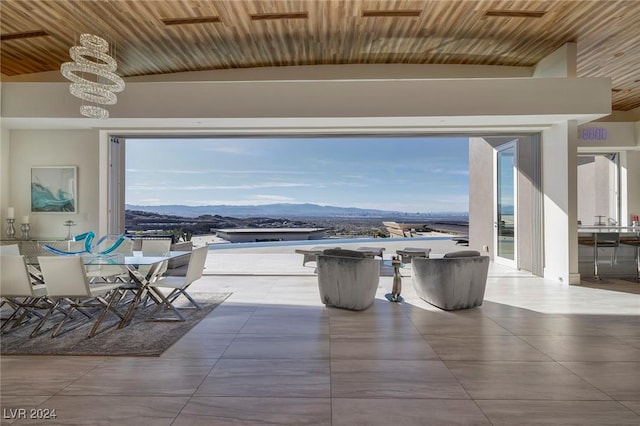 dining space with a mountain view, a healthy amount of sunlight, lofted ceiling, and an inviting chandelier