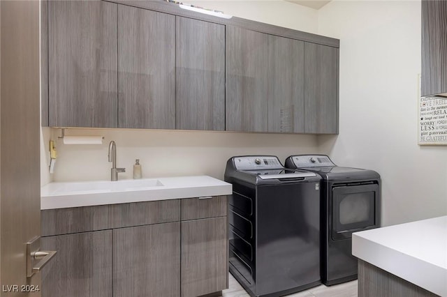 clothes washing area with sink, cabinets, and independent washer and dryer