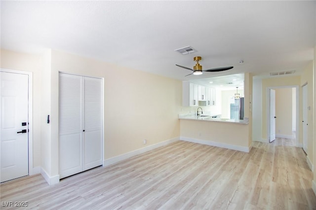 unfurnished living room with ceiling fan, light wood-type flooring, and sink