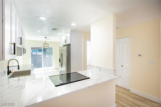 kitchen featuring white cabinets, sink, kitchen peninsula, and stainless steel refrigerator with ice dispenser