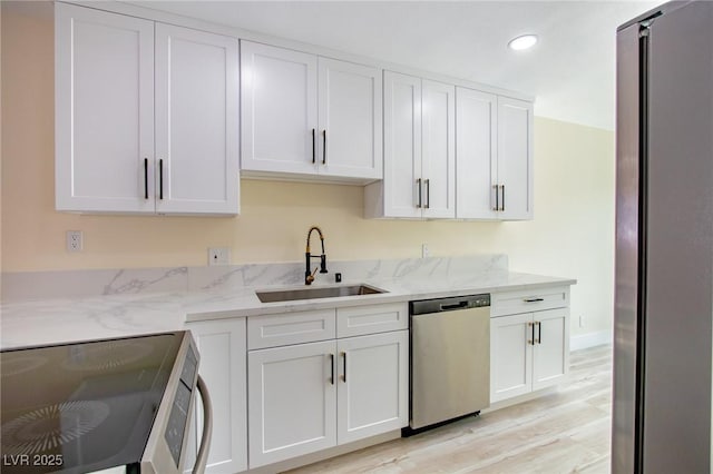 kitchen with white cabinetry, sink, stainless steel appliances, and light stone counters