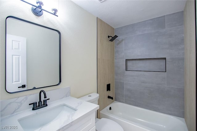 full bathroom with a textured ceiling, vanity, tiled shower / bath combo, and toilet