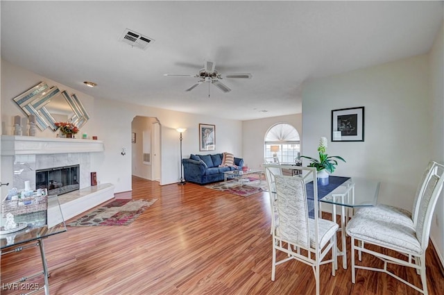 dining area with ceiling fan, a fireplace, and wood-type flooring