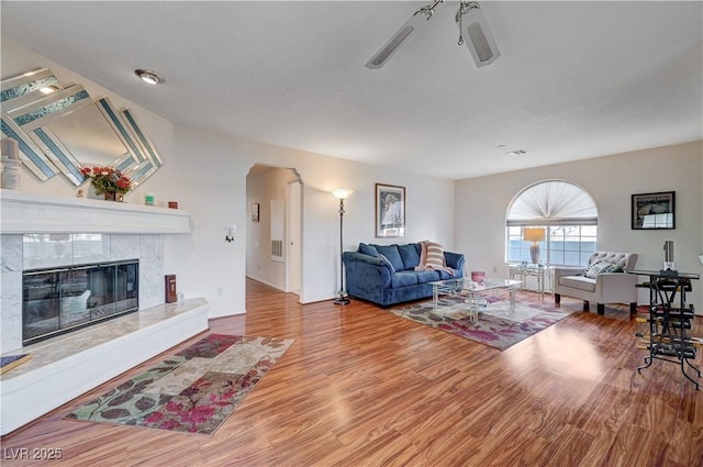 living room featuring hardwood / wood-style floors, ceiling fan, and a tile fireplace