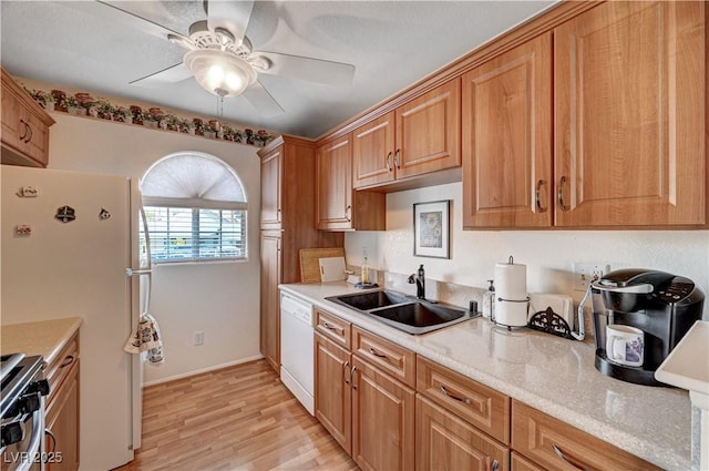 kitchen featuring light stone countertops, sink, ceiling fan, white appliances, and light wood-type flooring