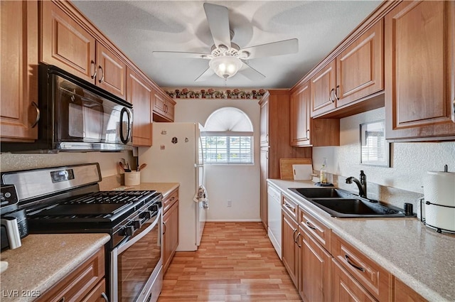 kitchen featuring white appliances, light hardwood / wood-style floors, ceiling fan, and sink