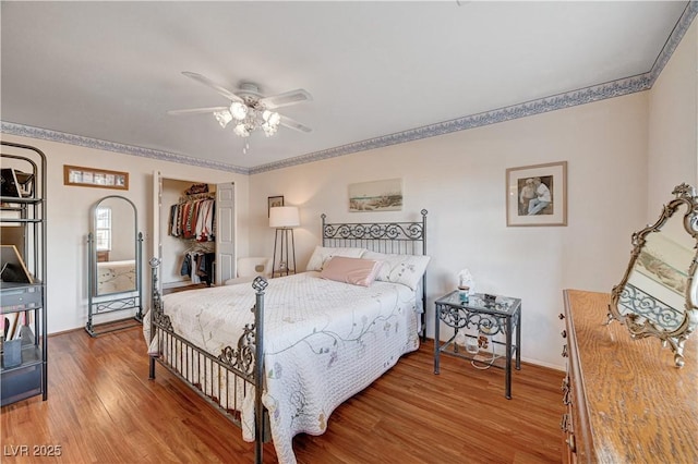 bedroom with ceiling fan, wood-type flooring, a walk in closet, and a closet