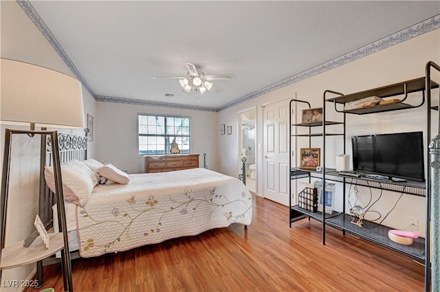 bedroom with ceiling fan, ornamental molding, ensuite bathroom, and wood-type flooring