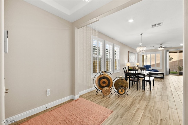 dining room featuring ceiling fan with notable chandelier and light hardwood / wood-style flooring