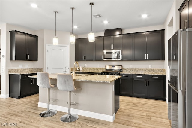 kitchen featuring appliances with stainless steel finishes, sink, pendant lighting, a center island with sink, and a breakfast bar area