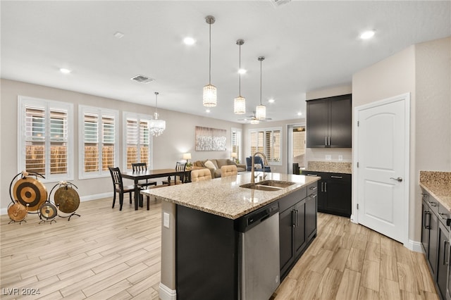 kitchen with dishwasher, a center island with sink, sink, ceiling fan, and light stone countertops