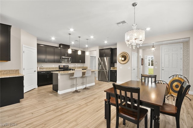 dining area featuring light hardwood / wood-style flooring, a notable chandelier, and sink