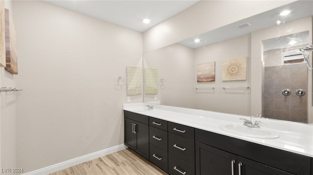 bathroom with hardwood / wood-style floors, vanity, and a shower