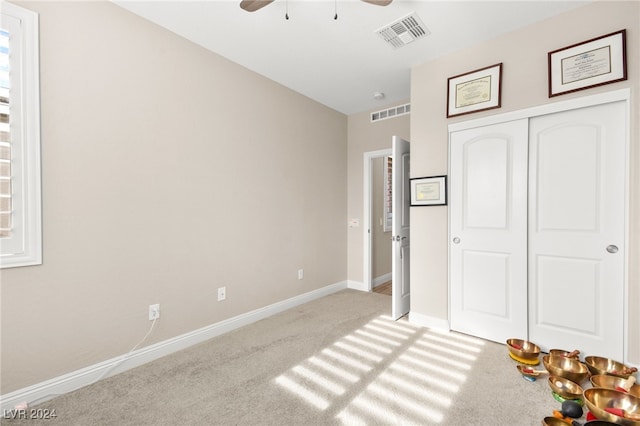 unfurnished bedroom with ceiling fan, light carpet, and a closet