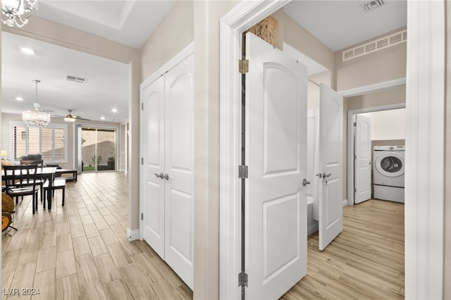 hallway with a chandelier, washer / clothes dryer, and light hardwood / wood-style floors