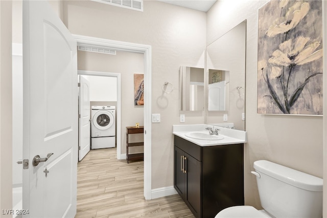 bathroom featuring toilet, hardwood / wood-style floors, vanity, and washer / dryer