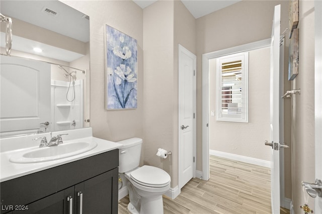 bathroom featuring walk in shower, hardwood / wood-style floors, vanity, and toilet