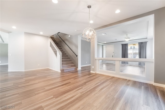 unfurnished living room with ceiling fan with notable chandelier and light hardwood / wood-style flooring