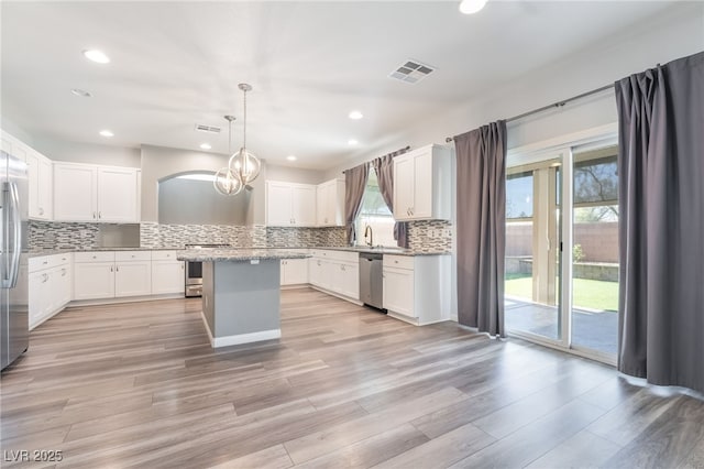 kitchen with pendant lighting, a center island, plenty of natural light, white cabinetry, and stainless steel appliances