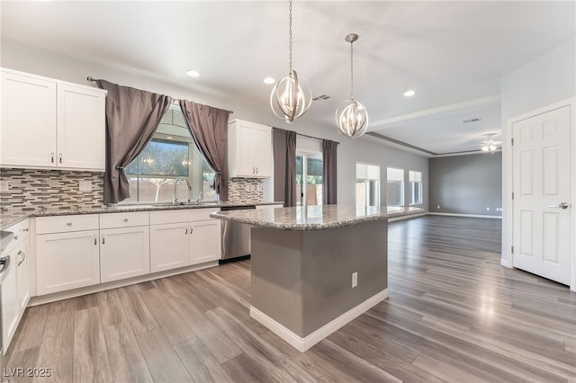 kitchen featuring dishwasher, light stone countertops, white cabinetry, and backsplash