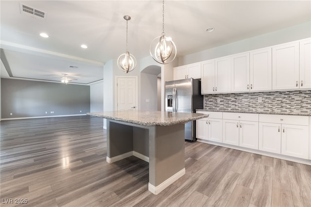 kitchen with a center island, white cabinetry, stainless steel fridge with ice dispenser, and hanging light fixtures