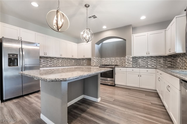 kitchen with decorative light fixtures, light stone counters, white cabinetry, and stainless steel appliances