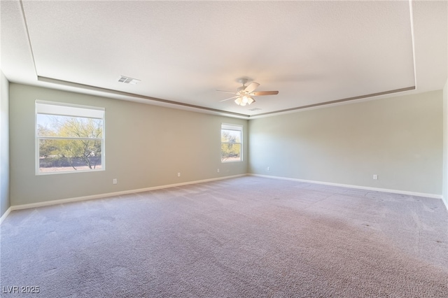 empty room with carpet flooring, ceiling fan, and a raised ceiling