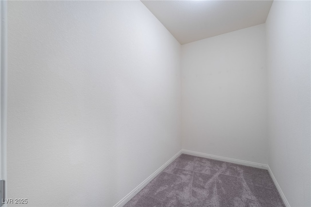 empty room featuring lofted ceiling and dark colored carpet