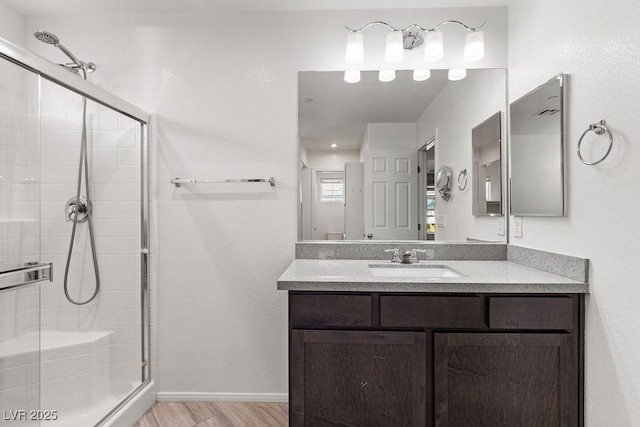 bathroom with vanity, a shower with shower door, and wood-type flooring