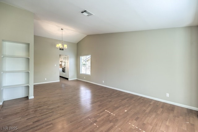 unfurnished room with dark hardwood / wood-style flooring, an inviting chandelier, and vaulted ceiling