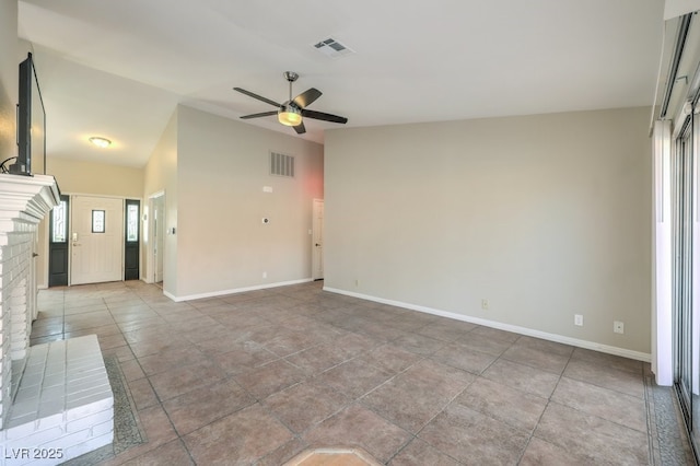 unfurnished room with ceiling fan and a brick fireplace