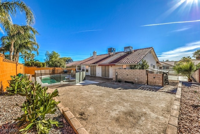 back of property featuring a fenced in pool and central AC unit