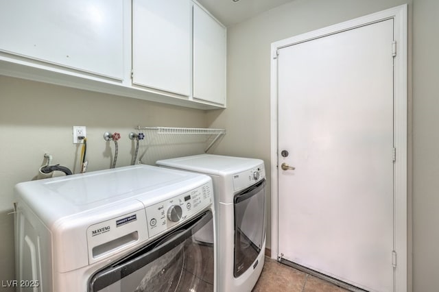 laundry area featuring washing machine and clothes dryer, light tile patterned flooring, and cabinets