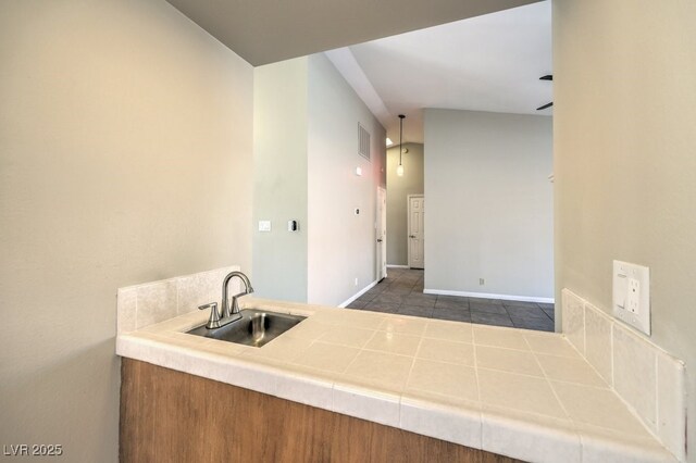 kitchen featuring tile countertops, dark tile patterned flooring, hanging light fixtures, and sink