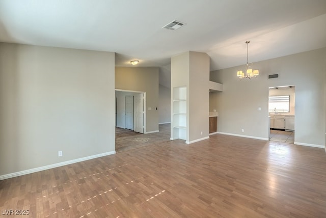 unfurnished room with a notable chandelier, built in features, sink, and light hardwood / wood-style flooring