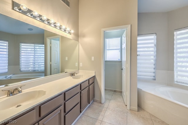 bathroom with tile patterned flooring, vanity, and a tub to relax in