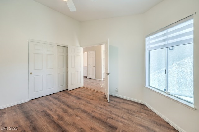 unfurnished bedroom with ceiling fan, a closet, and wood-type flooring