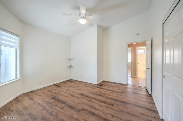 empty room featuring lofted ceiling, hardwood / wood-style flooring, ceiling fan, and a healthy amount of sunlight