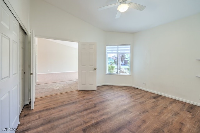 unfurnished bedroom with ceiling fan, a closet, wood-type flooring, and lofted ceiling