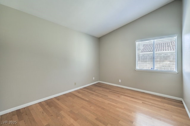 spare room with light wood-type flooring and lofted ceiling