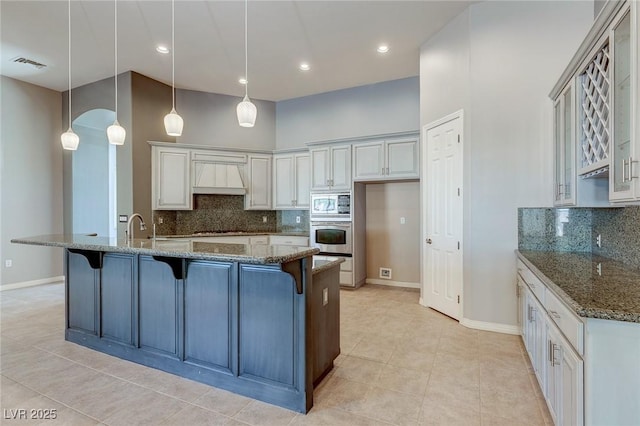 kitchen with a kitchen bar, built in microwave, dark stone counters, and stainless steel oven