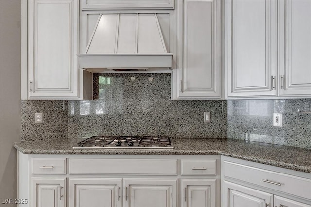 kitchen featuring decorative backsplash, custom range hood, and white cabinets