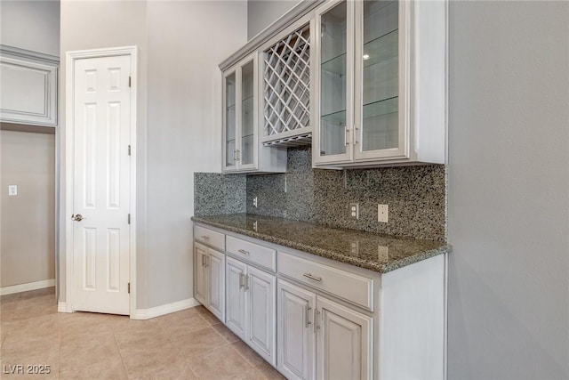 kitchen with decorative backsplash, light tile patterned flooring, and dark stone counters