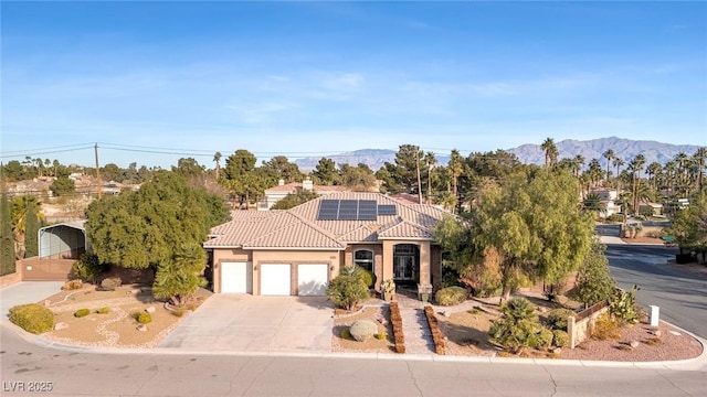 mediterranean / spanish home with solar panels, a garage, and a mountain view