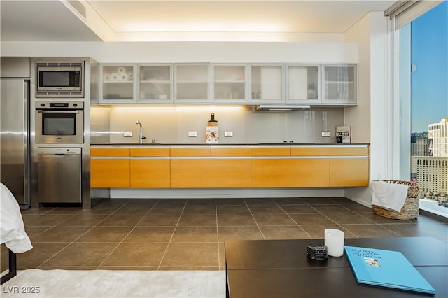 kitchen featuring floor to ceiling windows, dark tile patterned floors, stainless steel appliances, and ventilation hood