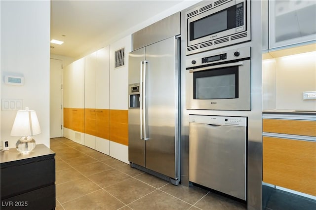 kitchen with dark tile patterned flooring, white cabinets, and appliances with stainless steel finishes